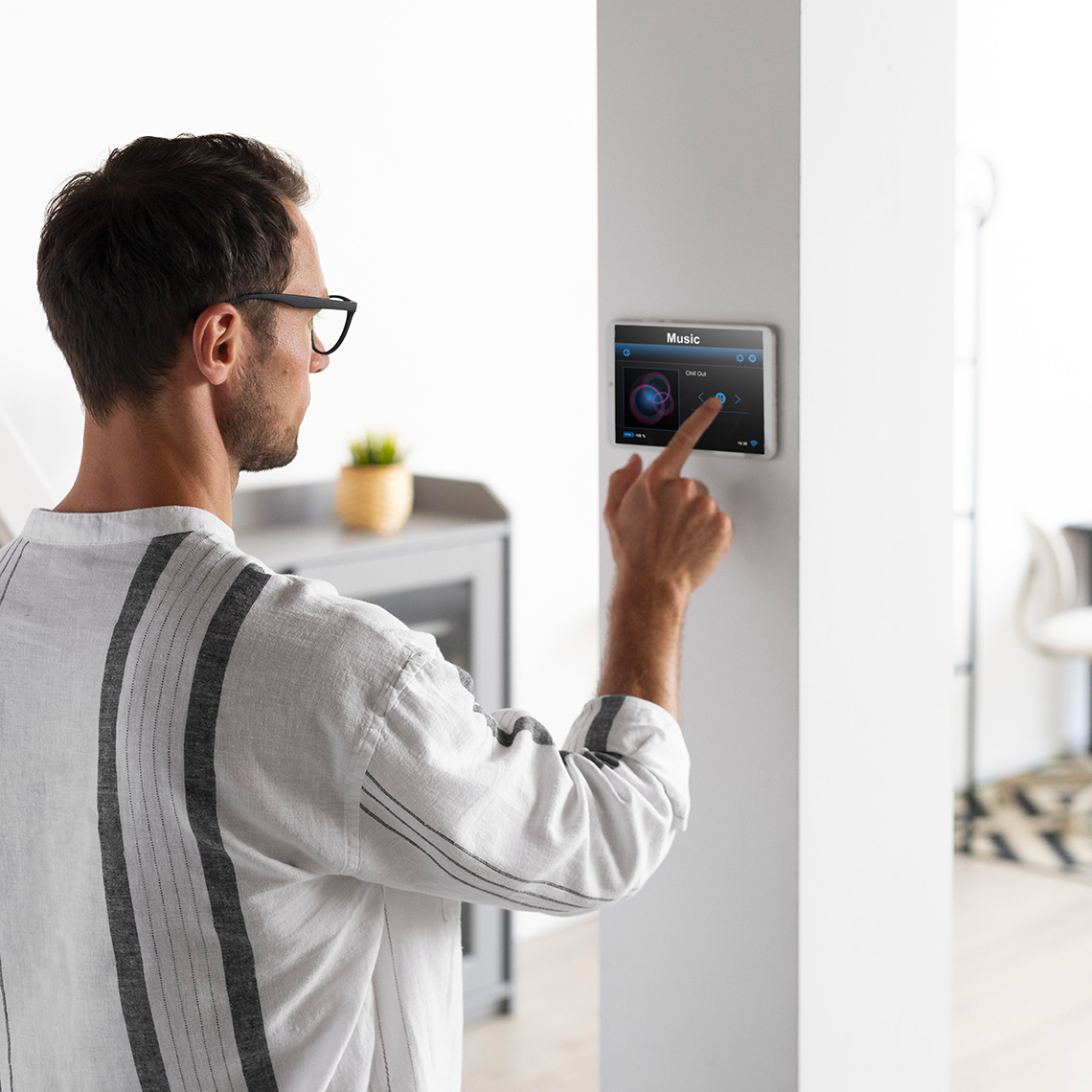 homme qui appuie sur sa tablette de contrôle de domotique pour lancer la musique vallée électricité votre partenaire électricien en gironde nouvelle aquitaine France